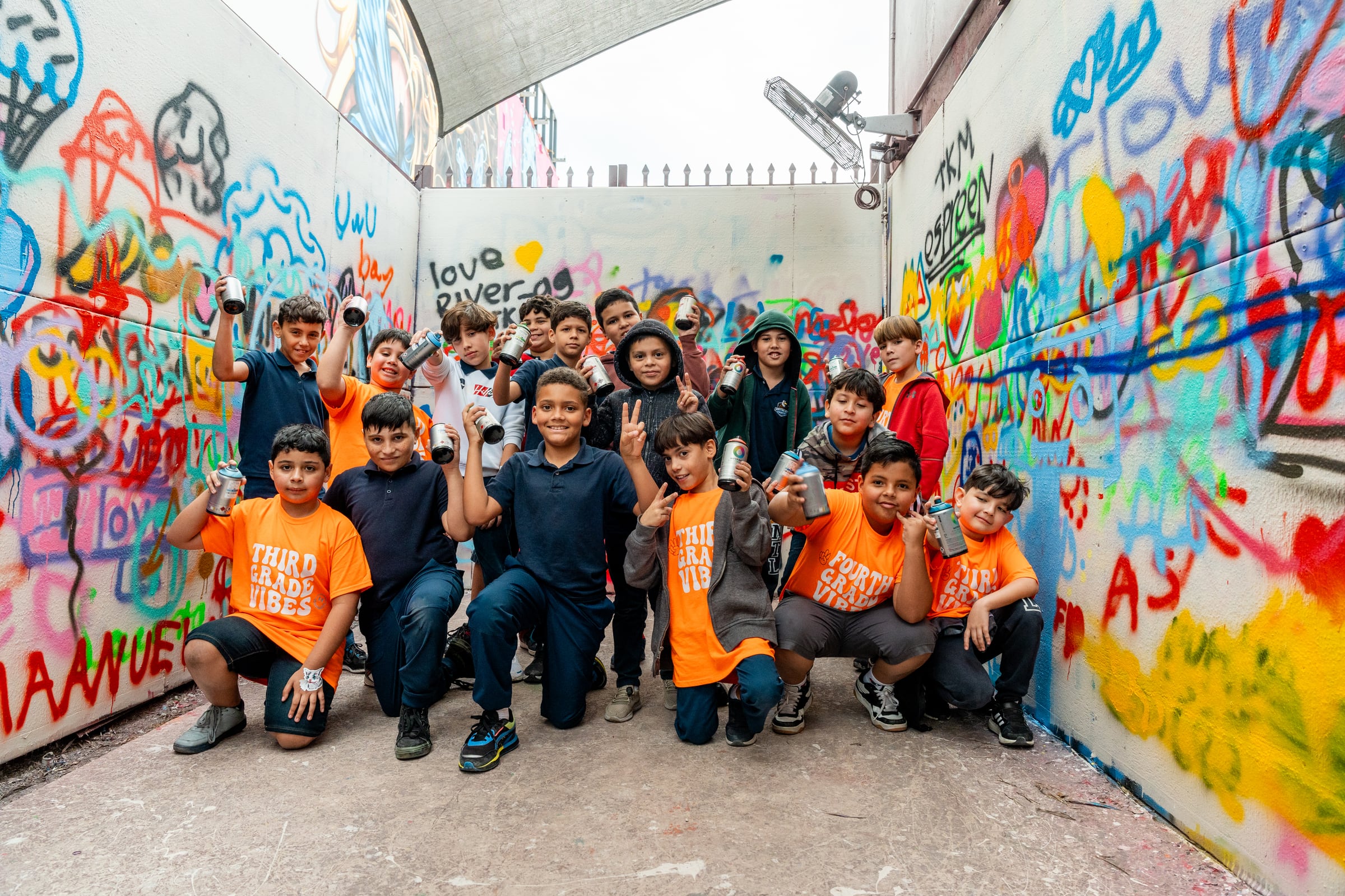 Students posing with spray cans after a field trip art activity at Wynwood Walls