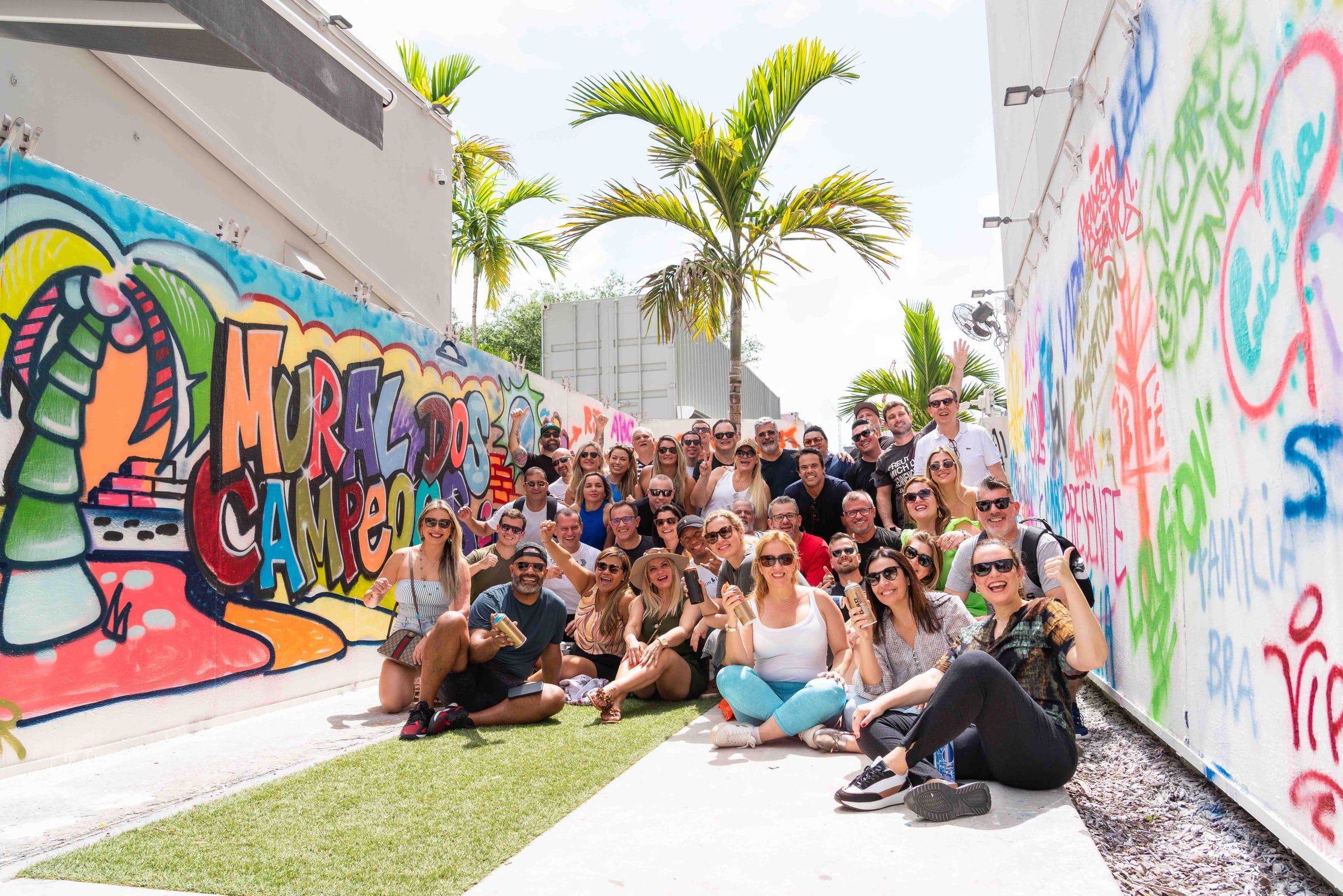 A group posing together between colorful graffiti walls at Wynwood Walls